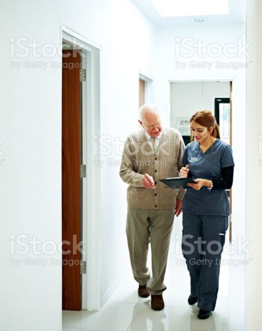 Female dentist discussing medical records with a older adult patient in a hallway