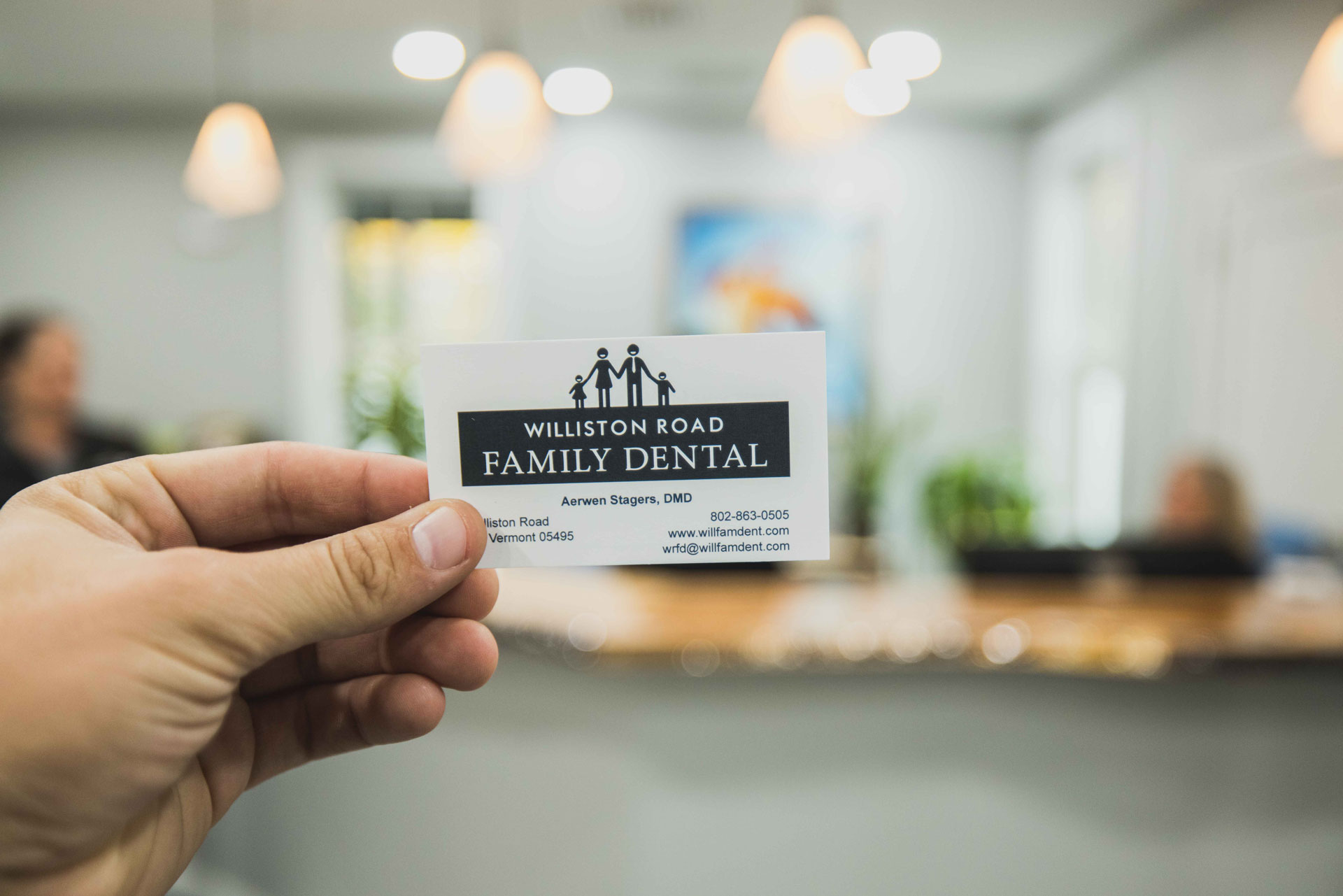 Hand holding a black and white Williston Road Family Dental business card